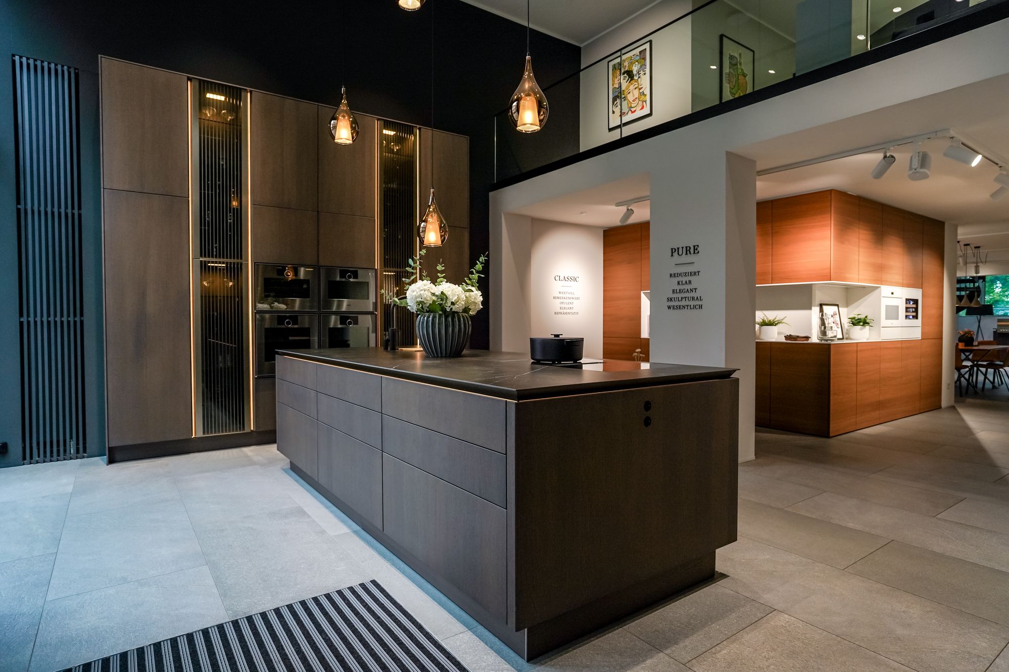 Kochinsel in dunkler Eiche vor beleuchteten Vitrinen im SieMatic Studio Leipzig