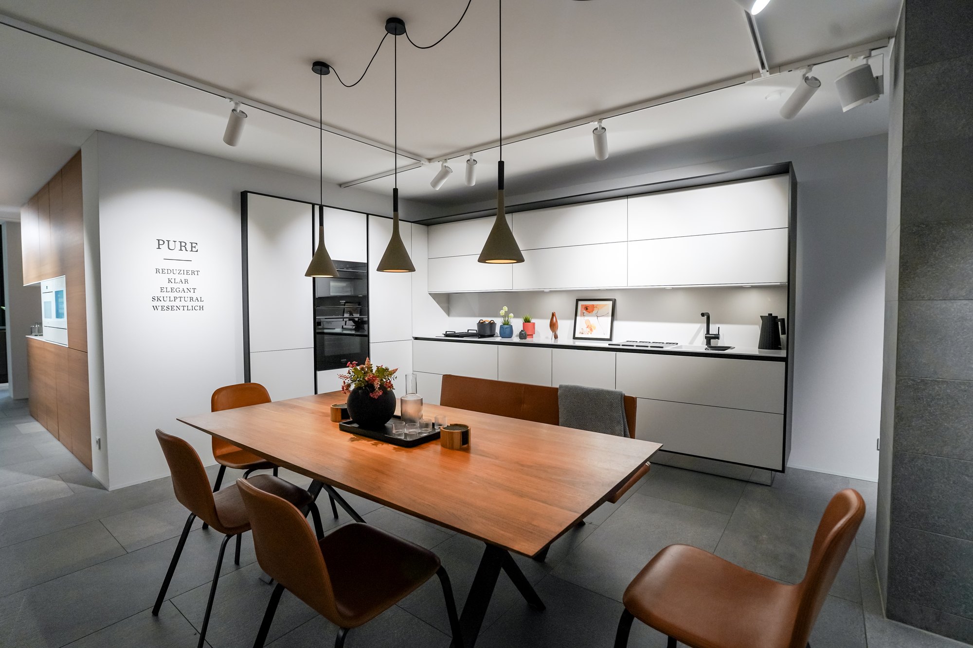 Weiße Küche der Stilwelt PURE mit Esstisch im SieMatic Studio Leipzig