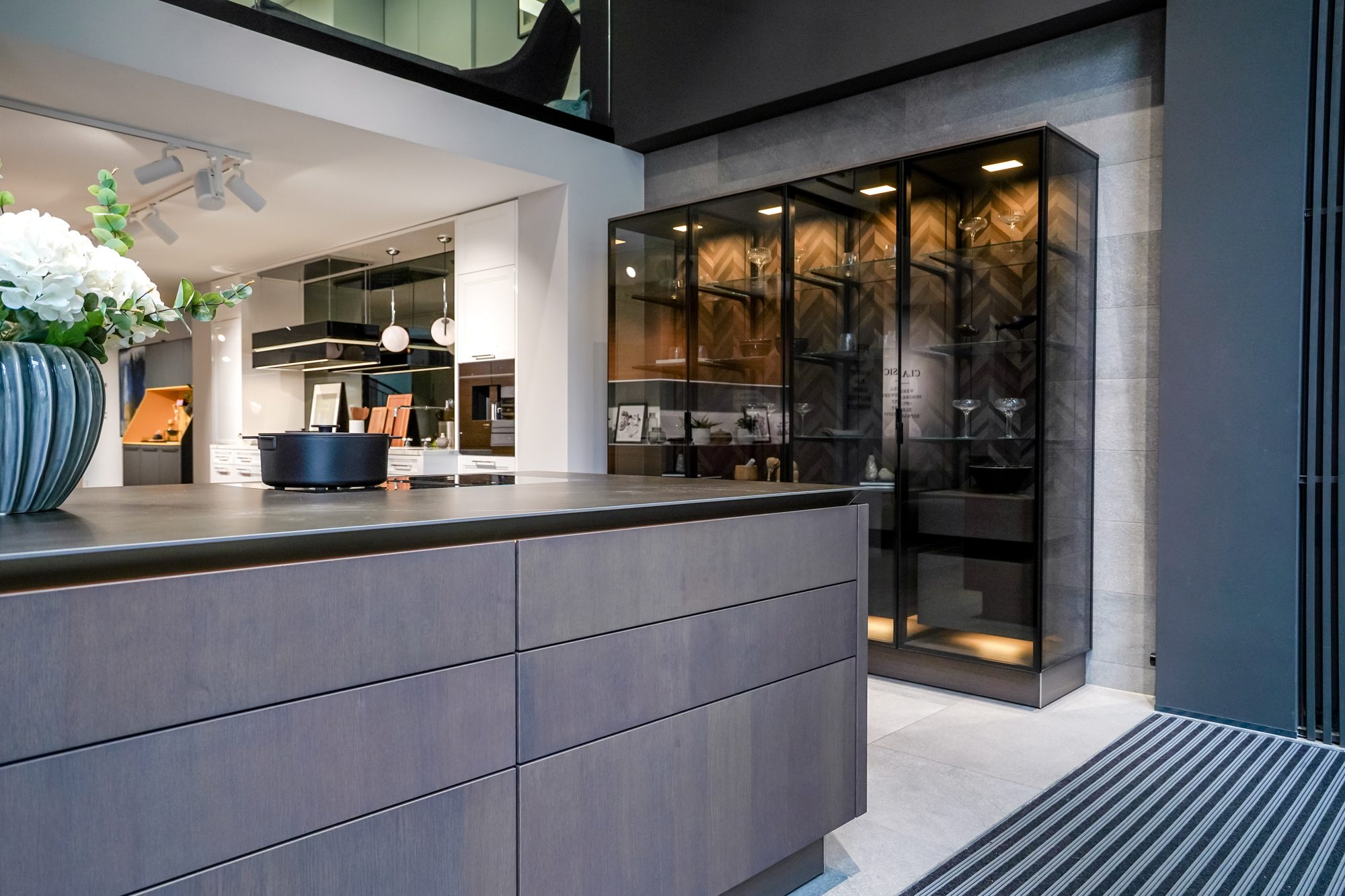 Kochinsel vor einer beleuchteten Glasvitrine im SieMatic Studio Leipzig